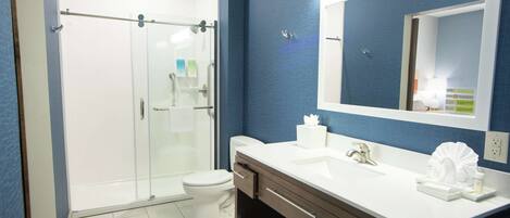 A modern bathroom with a glass shower enclosure, a white toilet, a vanity with a mirror, and a sink.