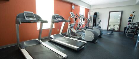A gym with treadmills, elliptical machines, and exercise balls.