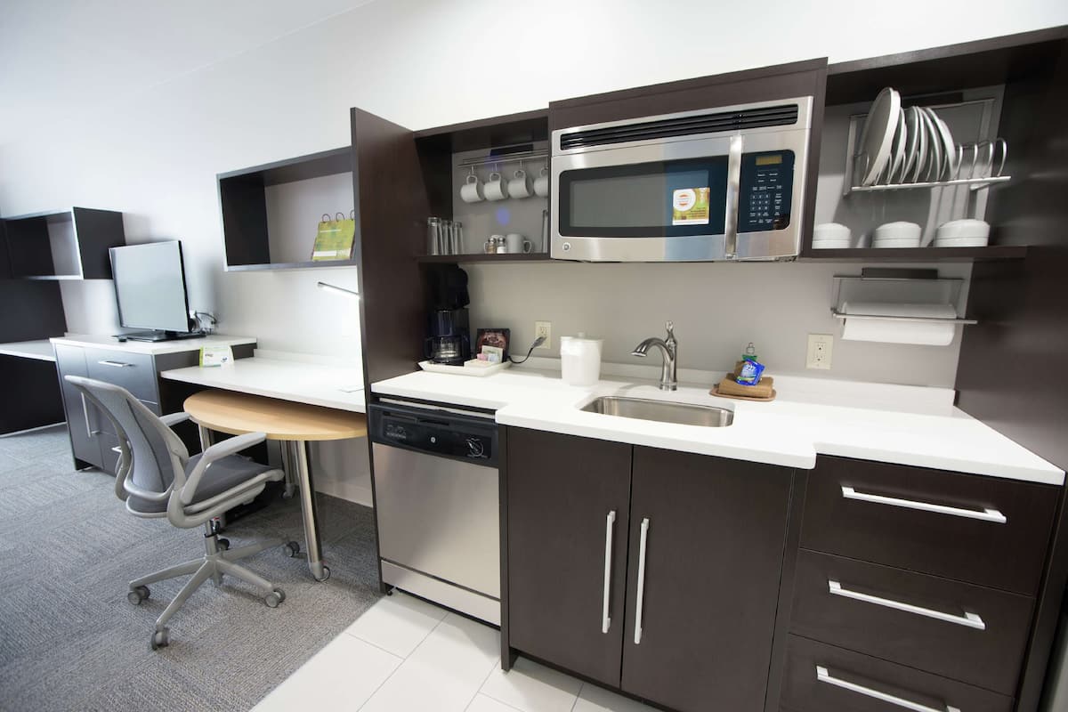 A modern kitchen with a built-in microwave, dishwasher, and a coffee station.