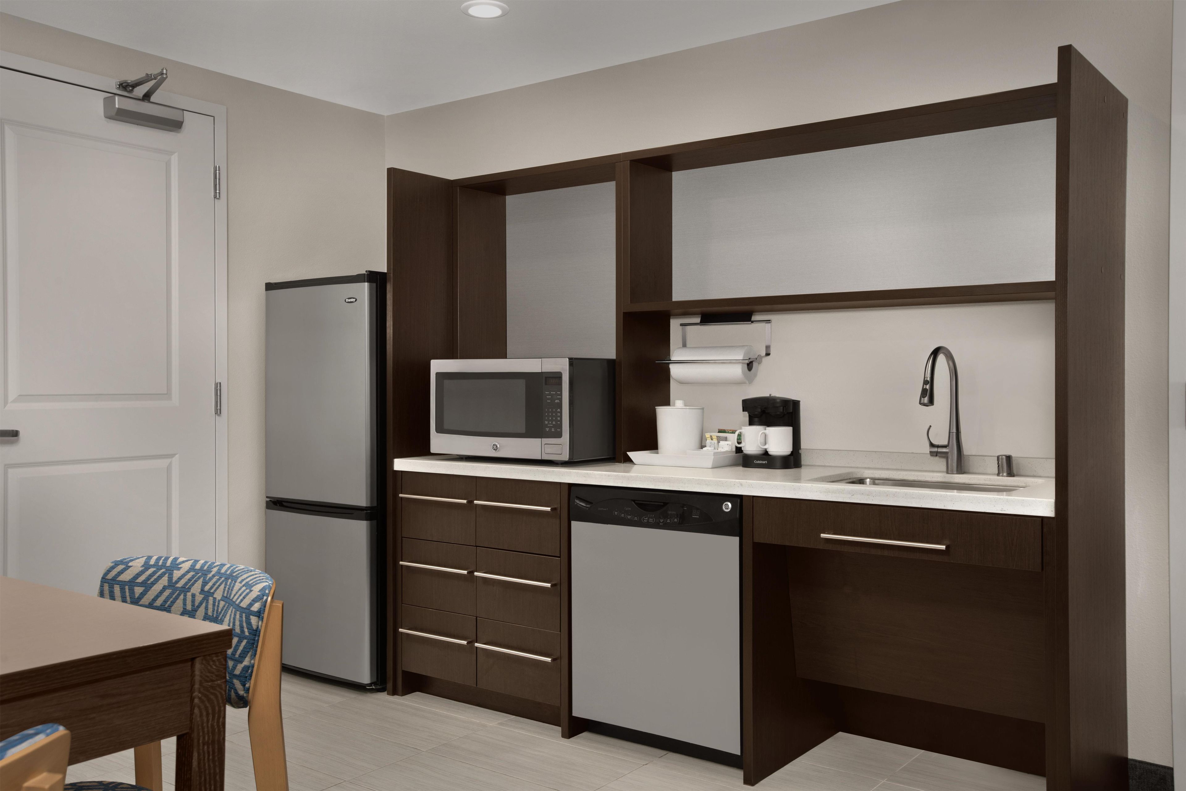 A compact kitchen with a refrigerator, microwave, coffee maker, and a sink.