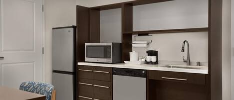 A compact kitchen with a refrigerator, microwave, coffee maker, and a sink.