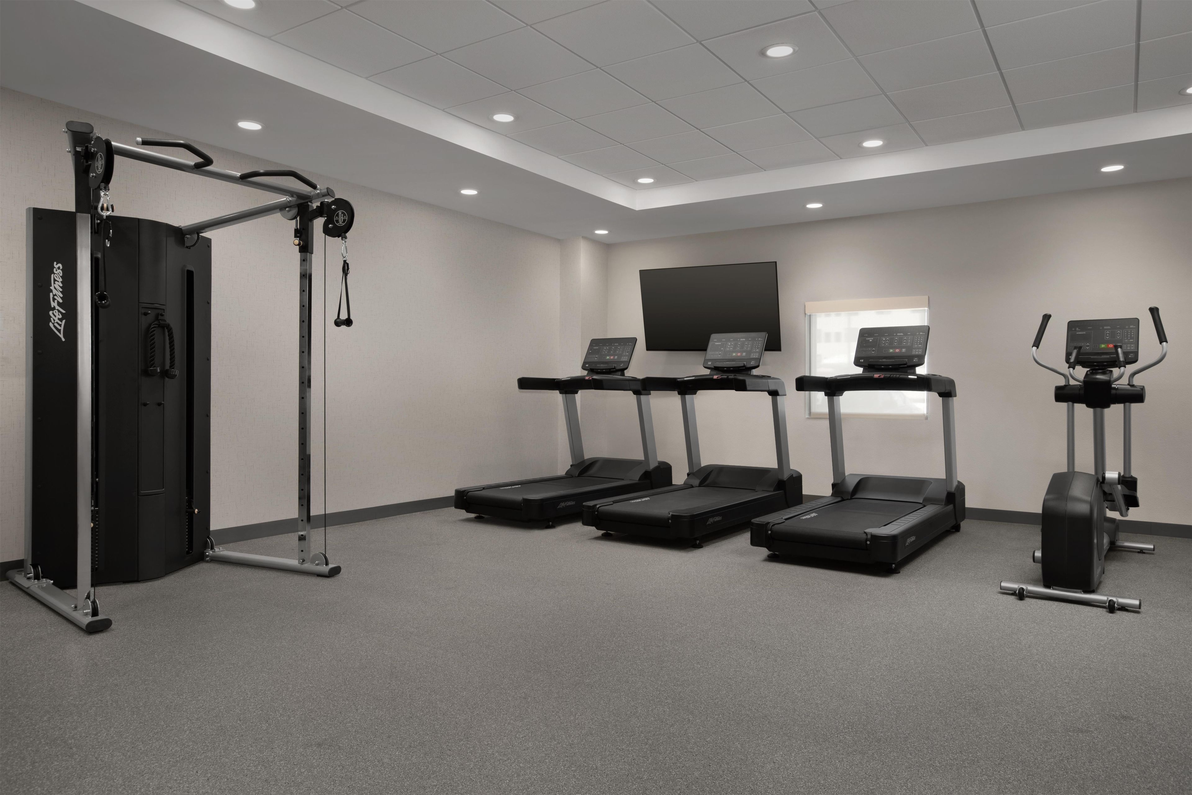 Un gimnasio equipado con cintas de correr, una máquina de pesas y una barra de dominadas.