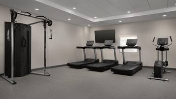 Un gimnasio equipado con cintas de correr, una máquina de pesas y una barra de dominadas.