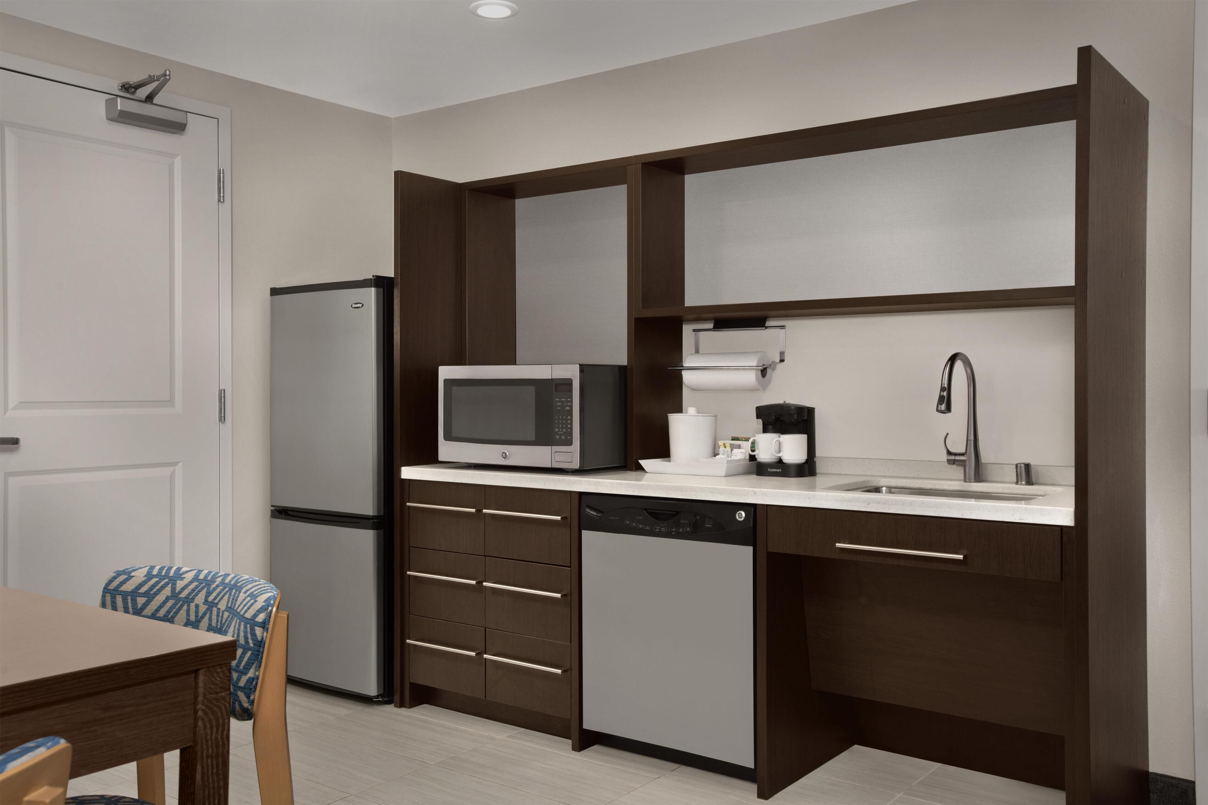 A modern kitchen with a refrigerator, microwave, coffee maker, and dishwasher.
