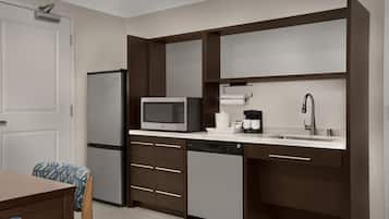 A modern kitchen with a refrigerator, microwave, coffee maker, and dishwasher.