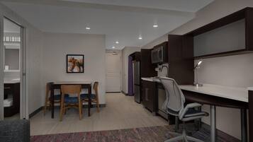 A modern kitchen with a dining area, a microwave, a refrigerator, and a desk with a chair.