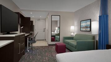 A hotel room with a bed, desk, chair, television, and a mirror.