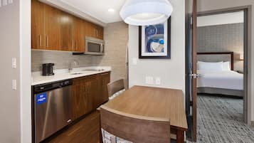 Quarto de hotel com cozinha compacta, cama e banheiro.