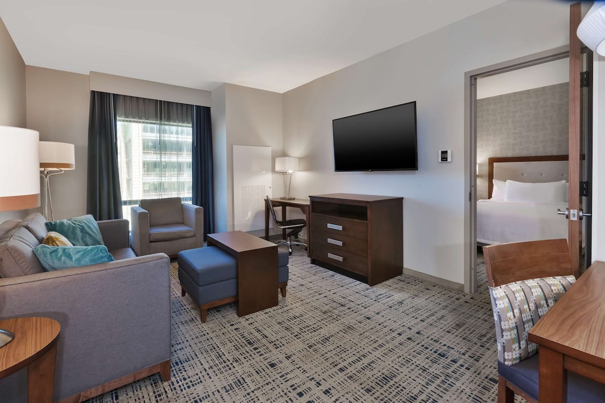 Een hotelkamer met een bank, een bureau, een televisie, een bed en een kamerbreed tapijt met dessin.
