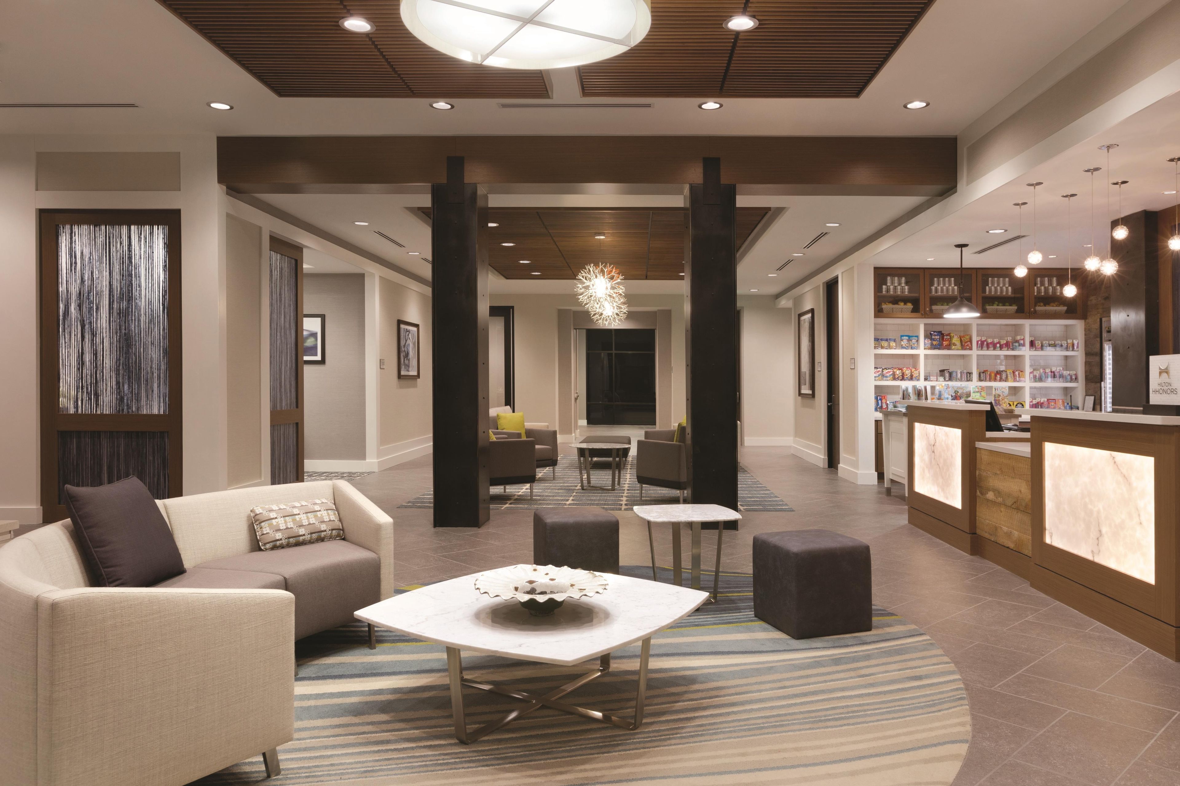 A hotel lobby with a reception desk, seating area, and a view into the dining area.