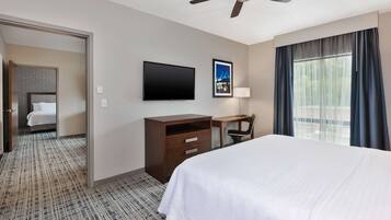 A hotel room with a bed, a desk, a chair, a television, and a window with curtains.