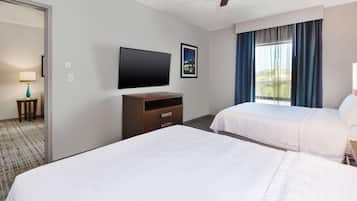 Quarto de hotel com duas camas, televisão de tela plana, ventoinha no teto e janela com cortinas.