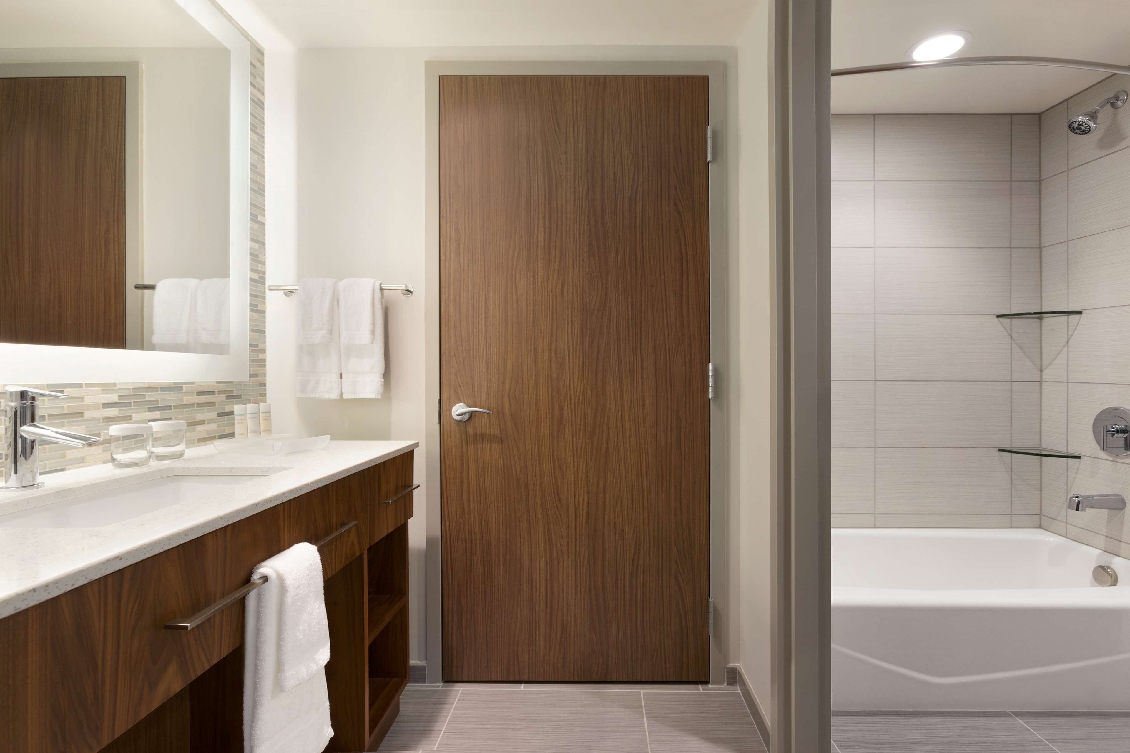 Une salle de bain moderne avec un meuble-lavabo en bois, une cabine de douche en verre et une baignoire blanche.