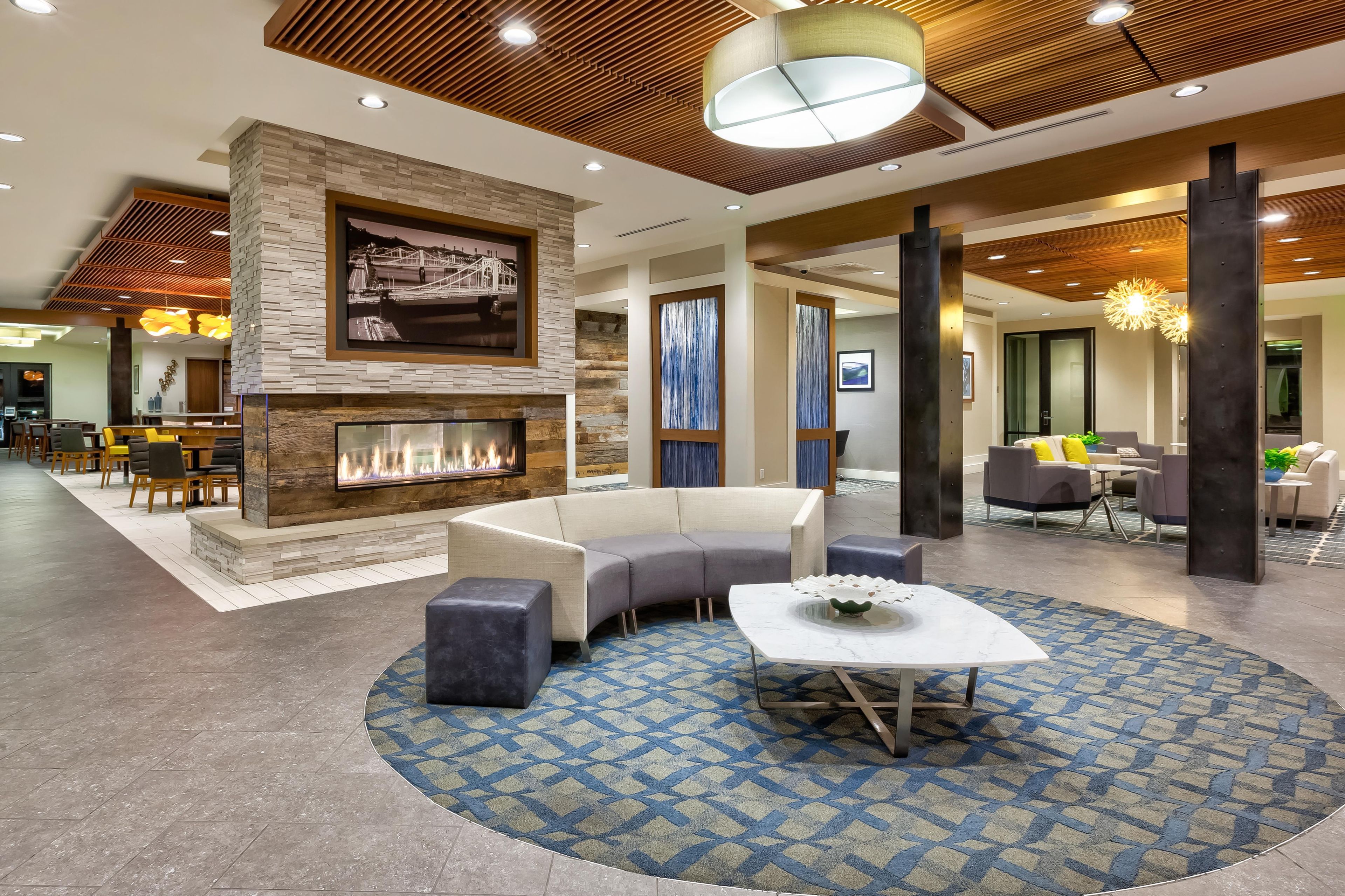 A modern lobby with a fireplace, seating area, and a dining space.