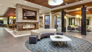 A modern lobby with a fireplace, seating area, and a dining space.