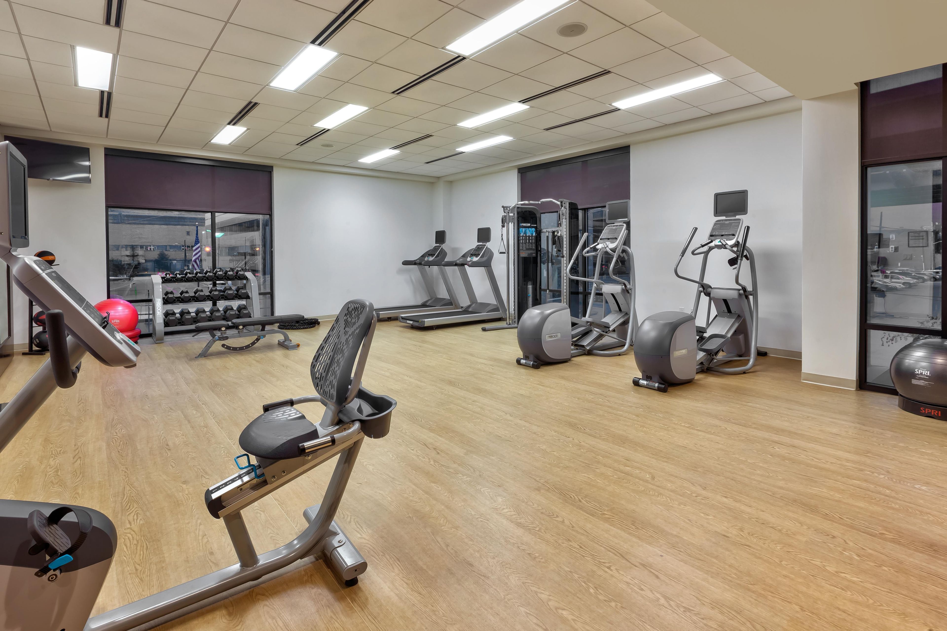 A gym with various exercise equipment, including treadmills, elliptical machines, and weightlifting stations.