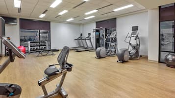 A gym with various exercise equipment, including treadmills, elliptical machines, and weightlifting stations.