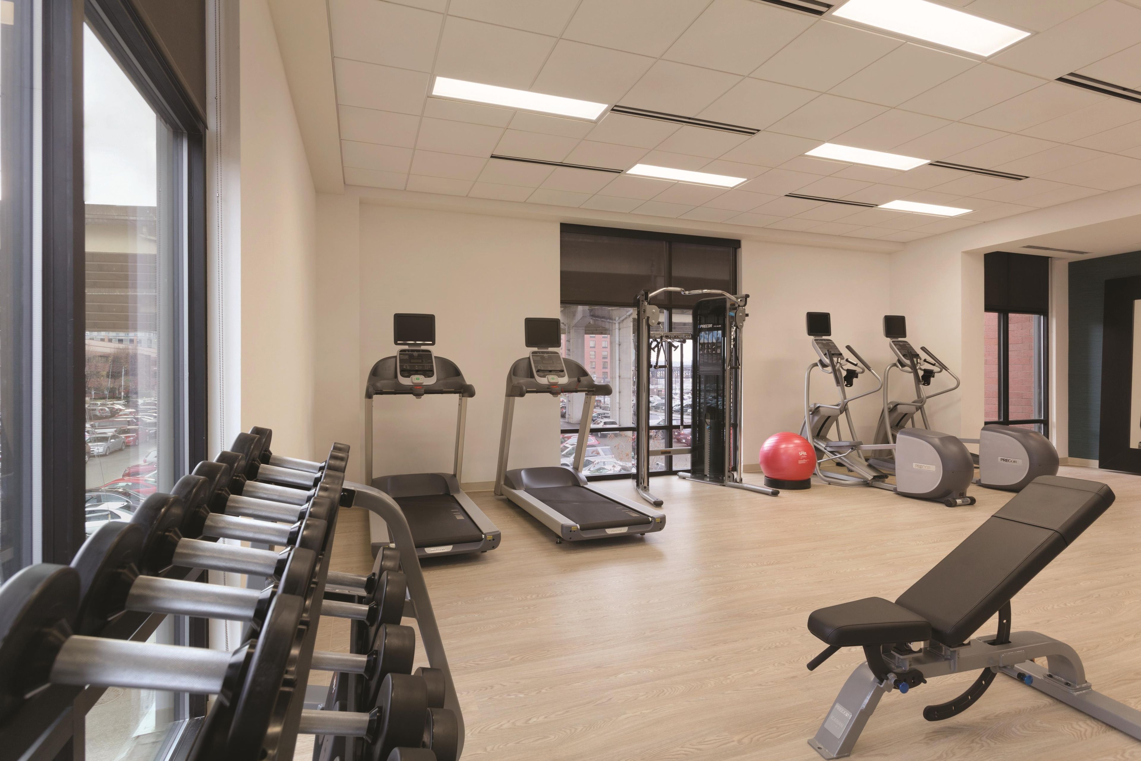 Ein Fitnessraum mit Laufbändern, Crosstrainern, einer Gewichtbank und einem Rudergerät.