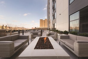 Un área de estar al aire libre con una chimenea, arquitectura de edificio moderna y cielo despejado.