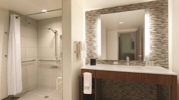 A modern bathroom with a shower, a vanity with a mirror, and a tiled floor.