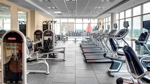 Une salle de sport équipée de tapis de course, d’appareils de musculation et d’autres équipements d’exercice.