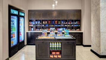 A self-service beverage station with refrigerated drinks and a selection of snacks and books.