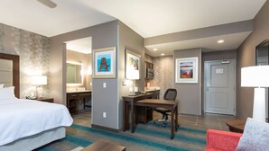 Une chambre d’hôtel avec un lit, un bureau, une chaise et un canapé rouge.