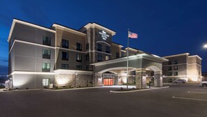 Un hôtel au design moderne, avec une façade en pierre et une enseigne indiquant « Homewood Suites ».