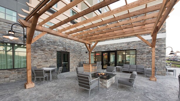 Une terrasse extérieure dotée d’un sol en pierre, d’une pergola en bois et d’un aménagement avec des sièges.
