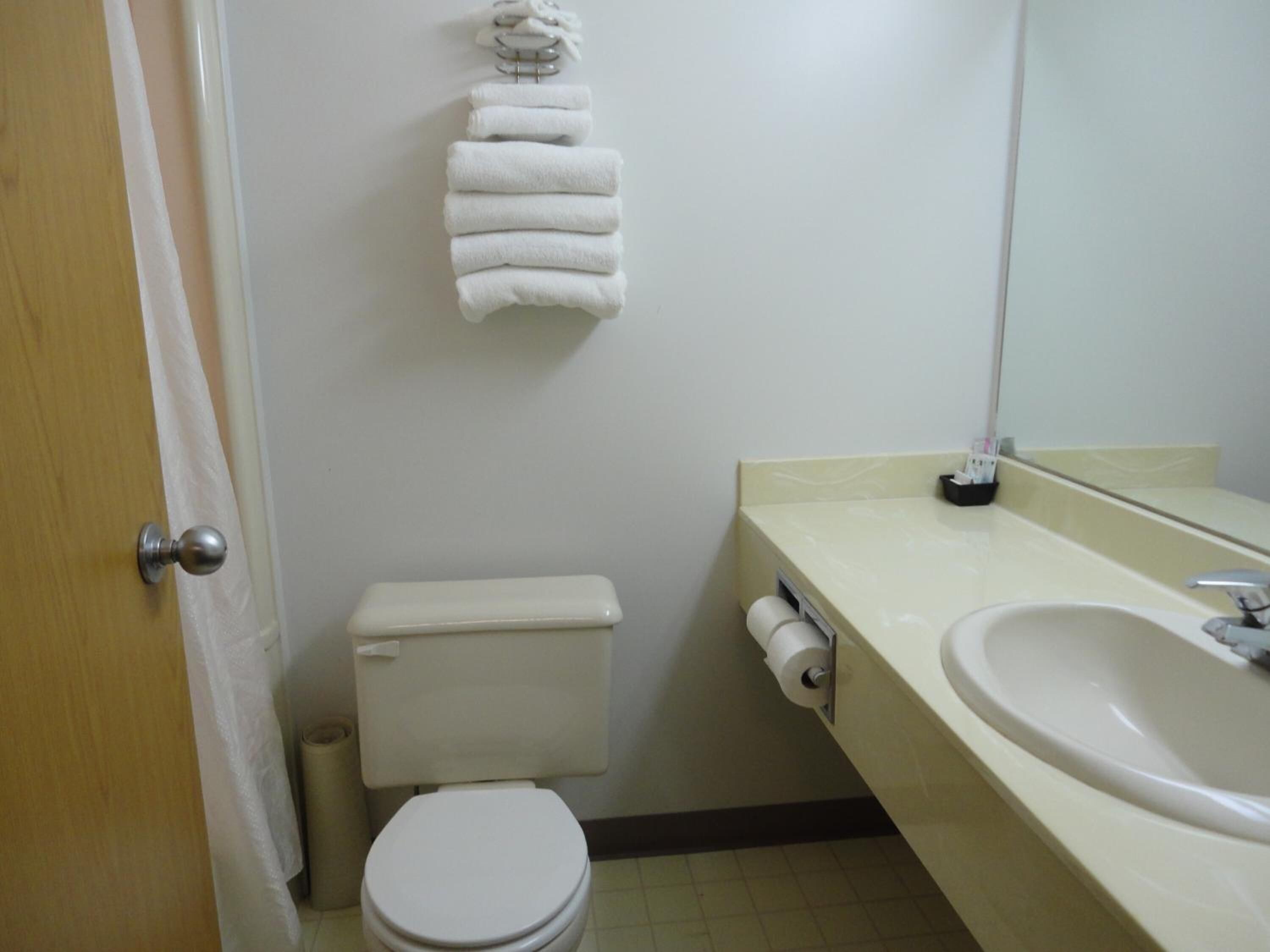 Un baño con inodoro, lavabo y toallero con toallas.