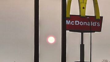 Une enseigne pour la chaîne d’hôtels Perfect Inns, avec le logo de McDonald’s en dessous, et une enseigne de magasin de cigarettes électroniques en arrière-plan.