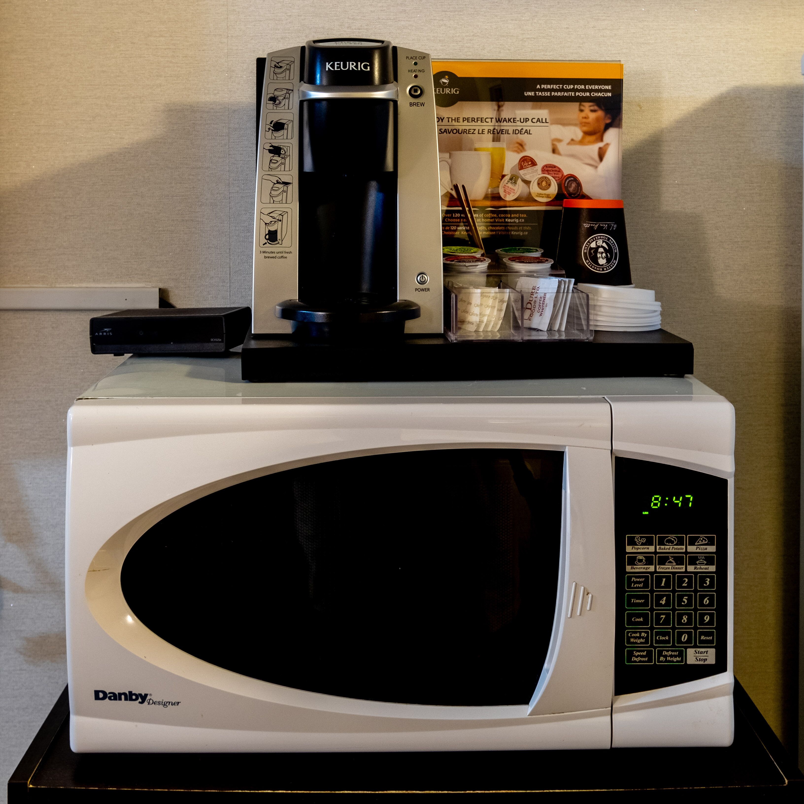 A microwave oven with a digital display and a coffee maker on top.