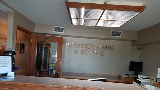 A reception desk area with a sign reading "Perfect Inns & Suites". - Perfect Inns & Suites (Weyburn)