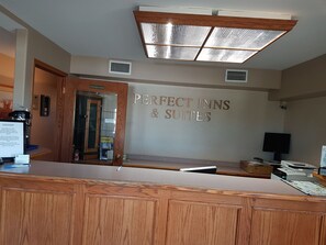 A reception desk area with a sign reading "Perfect Inns & Suites". - Perfect Inns & Suites (Weyburn)