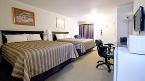 A hotel room with two beds, a desk, a chair, a television, and a door.