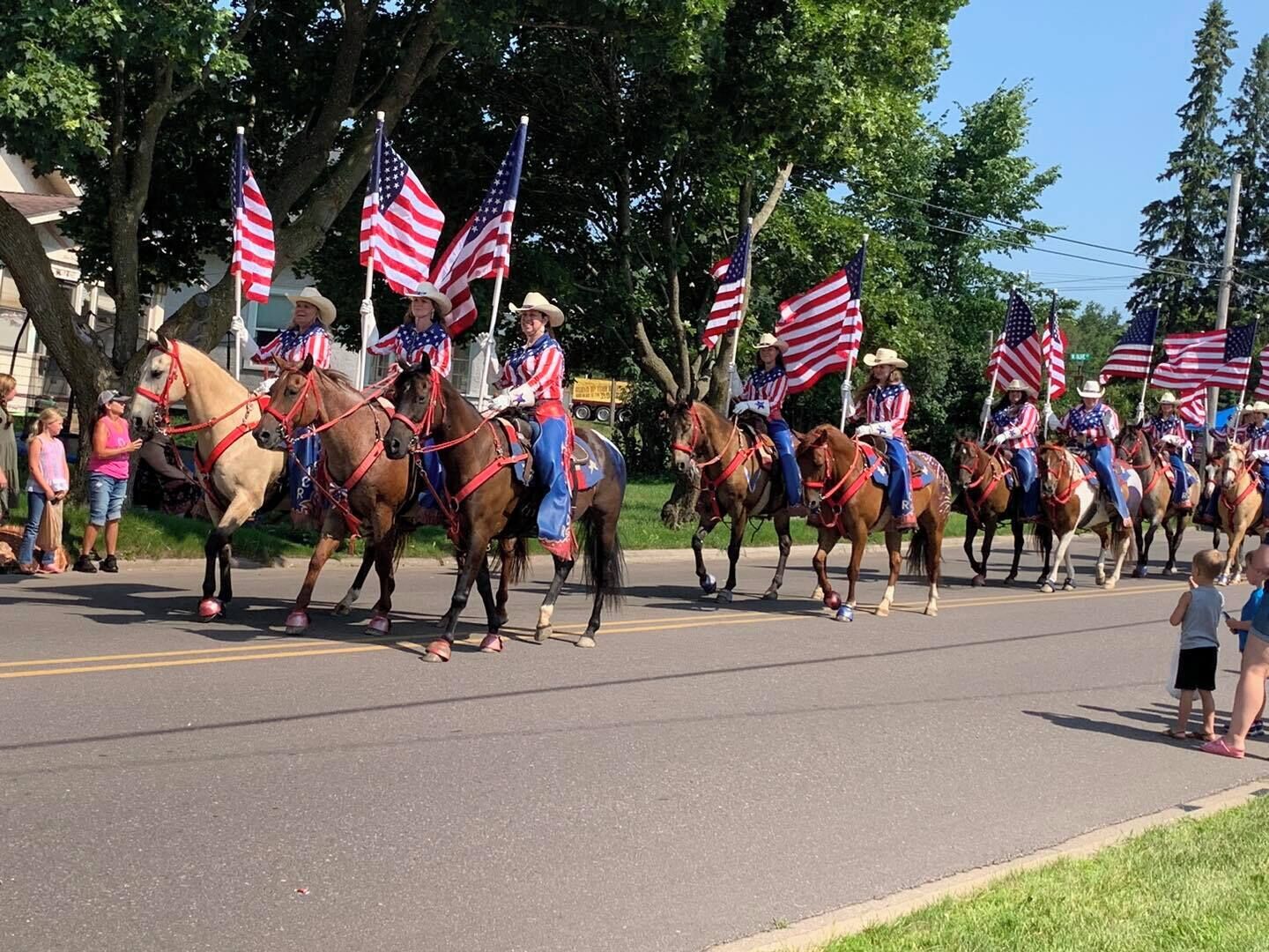 A parade with participants on horses carrying American flags.