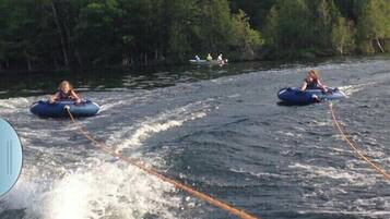 Two people on water tubes in a river surrounded by trees.
