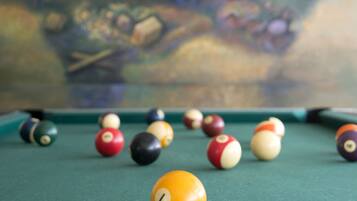 A pool table with various colored balls and a painting in the background.