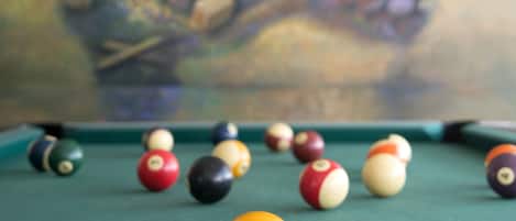 A pool table with various colored balls and a painting in the background.