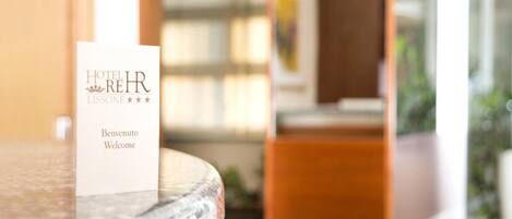 A hotel welcome card on a marble table with a blurred background of wooden furniture and a window.