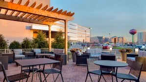 An outdoor patio with wicker furniture, a pergola, and a view of the cityscape. - Hampton Inn & Suites Rosemont Chicago O'Hare (Rosemont)