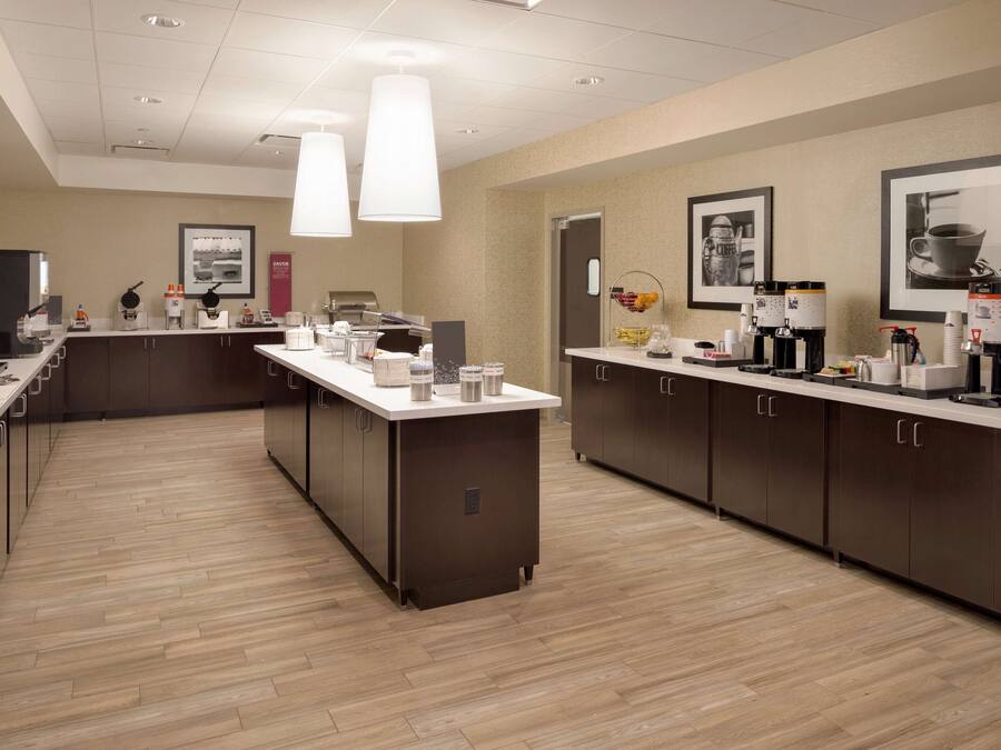 A modern kitchen with a central island, equipped with coffee machines and a variety of appliances.