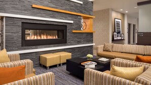 A modern living room with a fireplace, sofas, and a coffee table. - Hampton Inn & Suites Rosemont Chicago O'Hare (Rosemont)