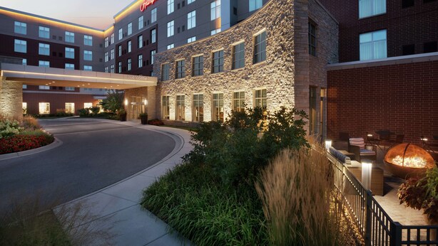 A hotel with a stone facade, multiple windows, and a well-lit entrance. - Hampton Inn & Suites Rosemont Chicago O'Hare (Rosemont)