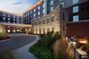 A hotel with a stone facade, multiple windows, and a well-lit entrance. - Hampton Inn & Suites Rosemont Chicago O'Hare (Rosemont)