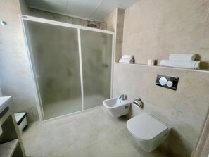 A modern bathroom with a shower, bidet, and toilet. - Complejo Lago Playa (Formentera)