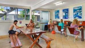 Une pièce avec une table et des bancs en bois, des ordinateurs et des affiches au mur.