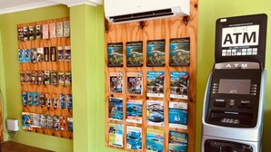 Un mur où sont affichées des brochures de voyage et un distributeur automatique de billets.