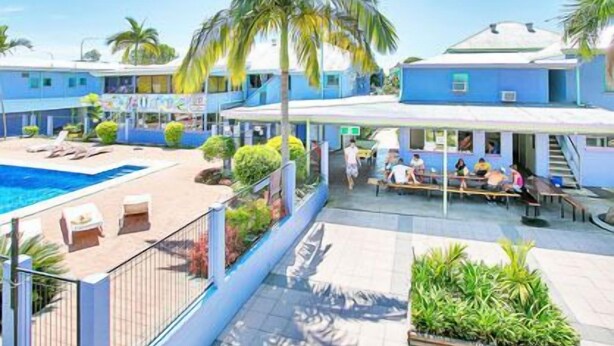 Un complexe hôtelier doté d’une piscine, d’un espace extérieur aménagé et de palmiers.