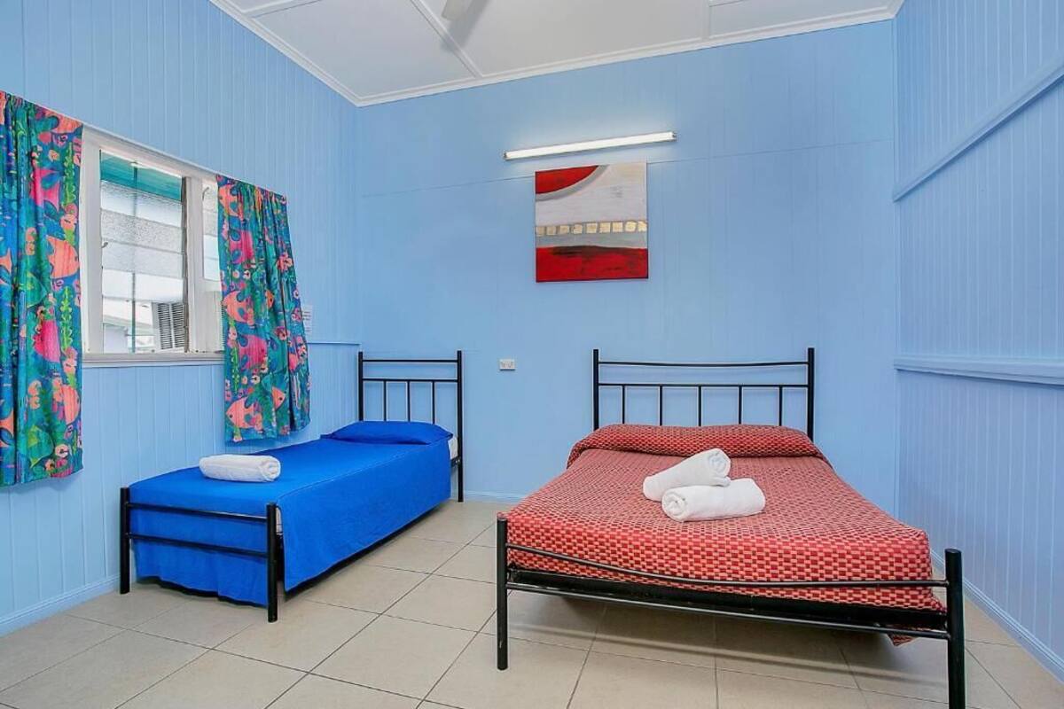 A room with two beds, one blue and one red, with matching pillows and towels.